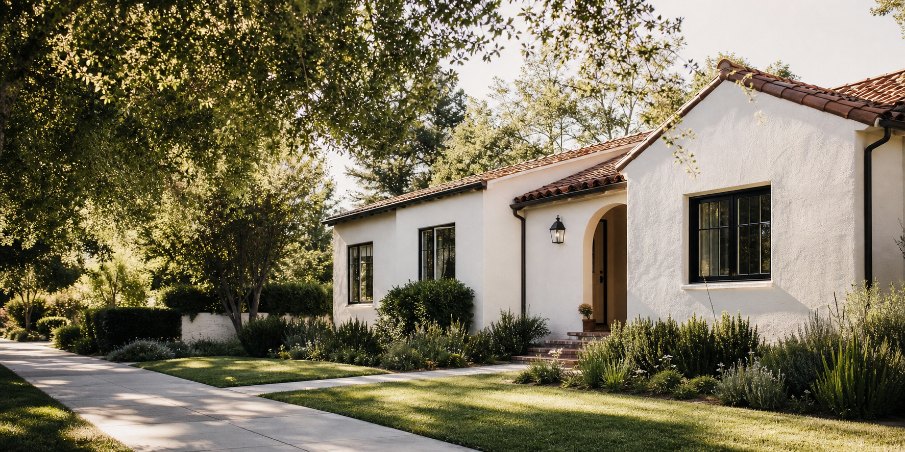 White stucco single-story home with a tile roof and landscaped front yard in daylight